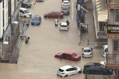 Yağmurda mahsur kalan motosikletli çareyi otomobilin üzerine çıkmakta buldu